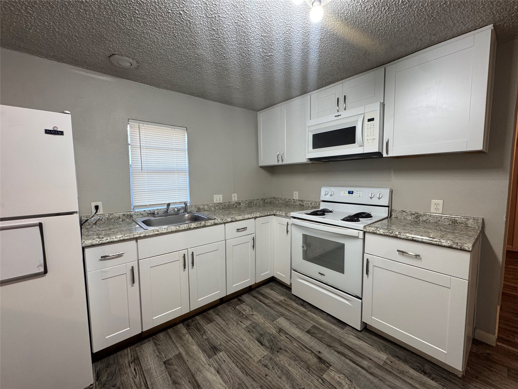 5007 Heflin Lane Austin, TX 78721 - Photo 9 of 25 Modern kitchen with sleek white cabinetry and granite-style countertops.