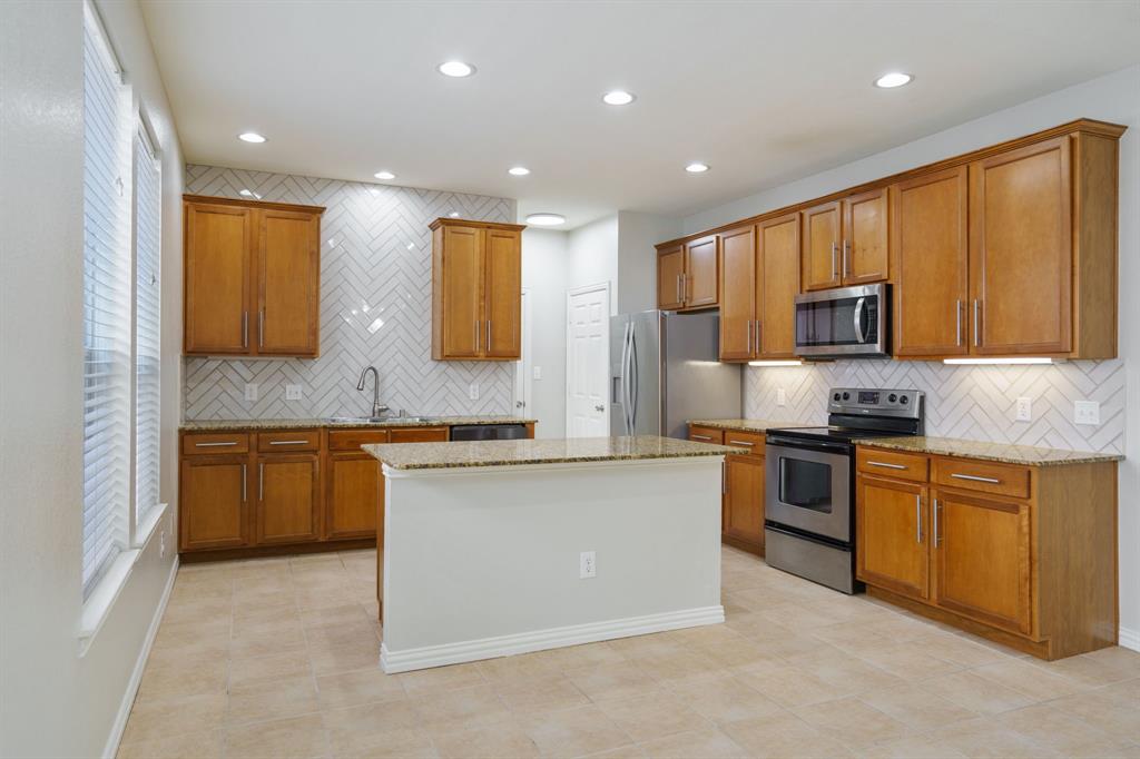 6407 Capulet Place Dallas, TX 75252 - Photo 4 of 33 a kitchen with stainless steel appliances granite countertop wooden cabinets a stove a sink and a refrigerator