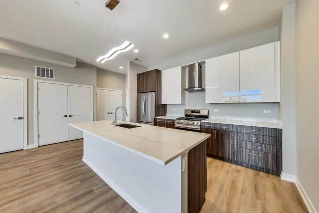 a large kitchen with kitchen island a sink dishwasher a stove and white cabinets with wooden floor