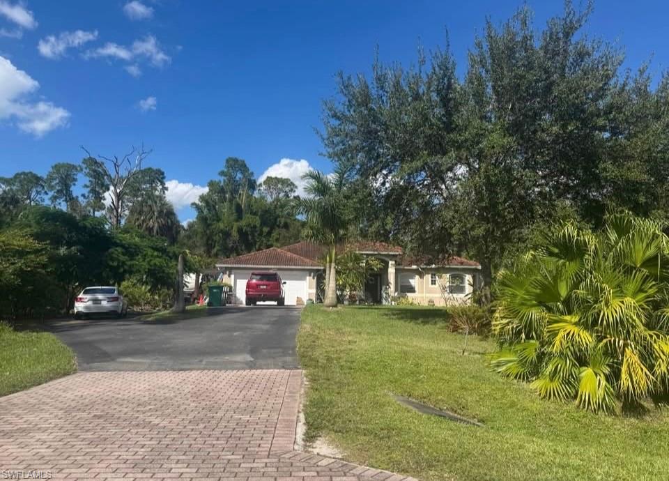 View of front of house with a front yard, driveway, and an attached garage