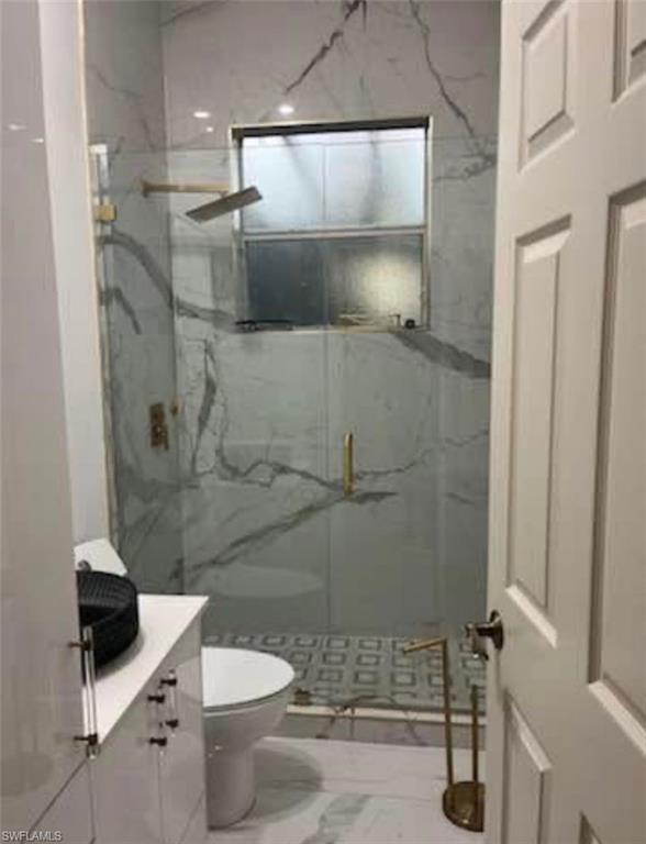 2841 12th Avenue Northeast Naples, FL 34120 - Photo 7 of 9 Full bathroom with vanity, a marble finish shower, and marble look tiles