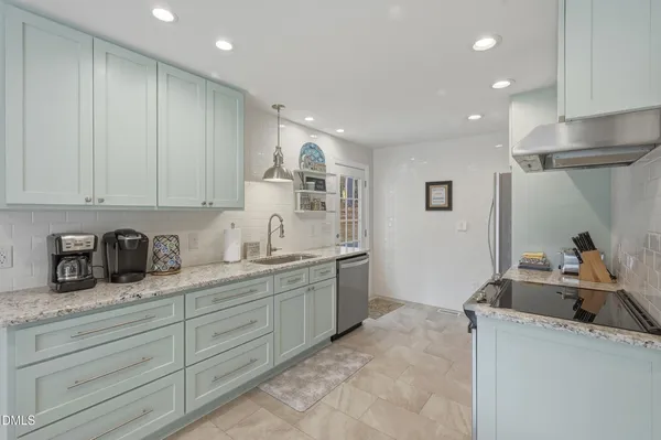 a kitchen with granite countertop a sink and white cabinets
