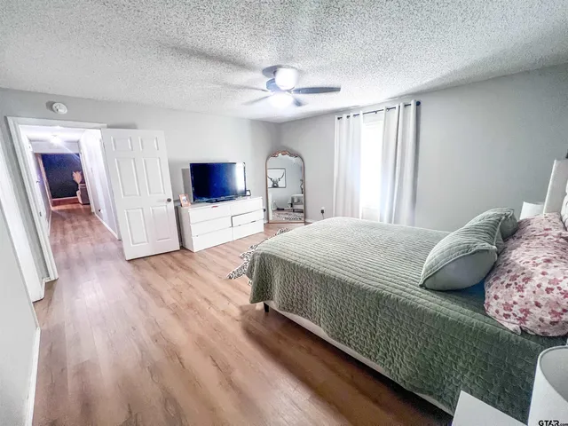 a bedroom with a large bed and a flat tv screen on dresser