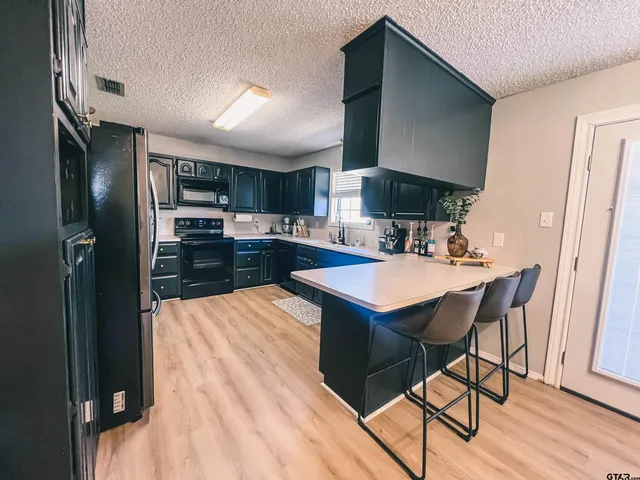 a kitchen with stainless steel appliances kitchen island granite countertop a table chairs in it and wooden floors