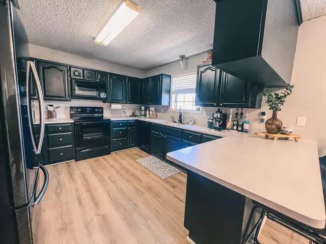 a kitchen with stainless steel appliances kitchen island granite countertop a sink dishwasher stove and refrigerator with wooden floor