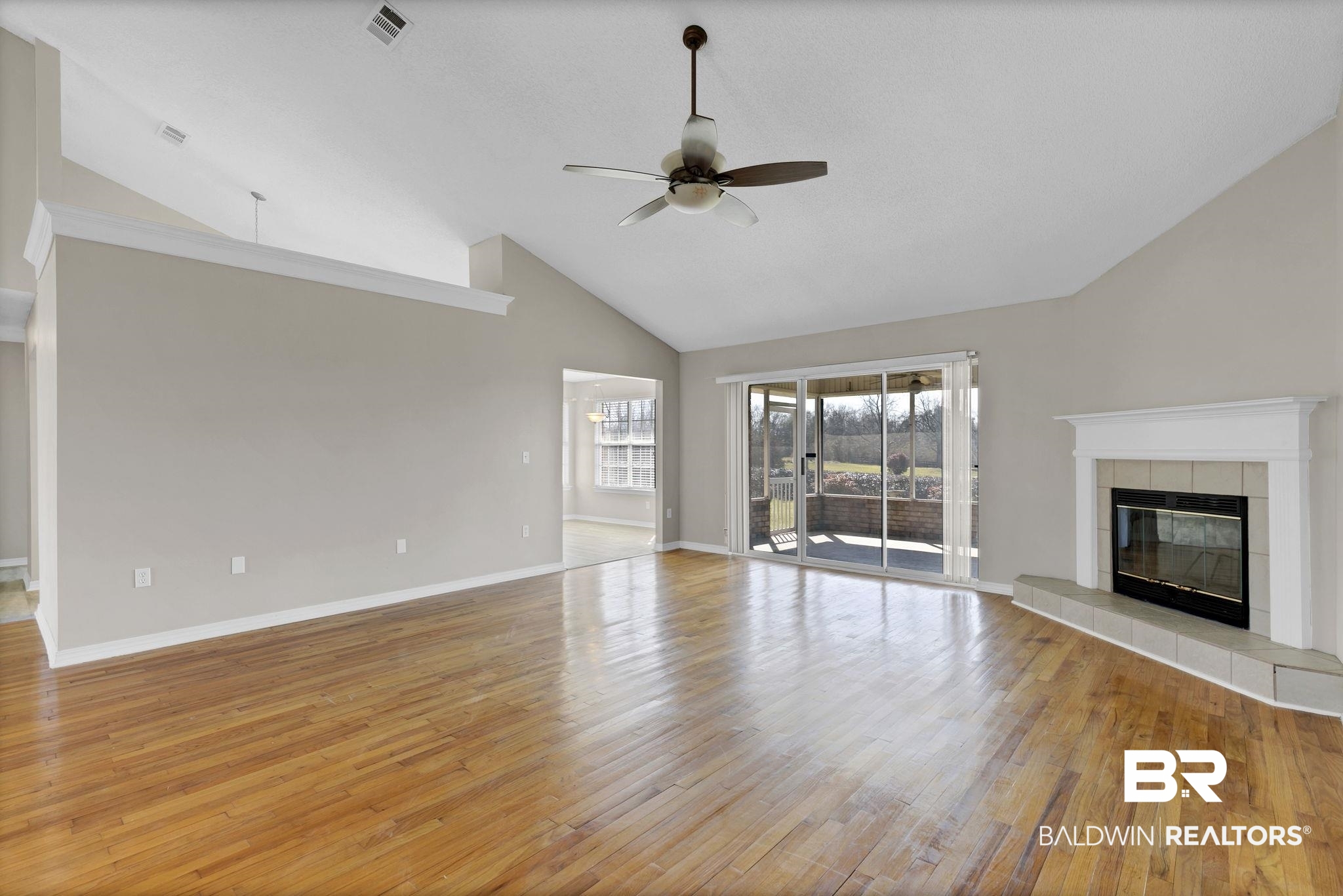 10238 Grove Drive Fairhope, AL 36532 - Photo 38 of 39 Living room Cathedral ceilings , a woodburning fireplace, ceiling fan, and light hard wood flooring showing the Open floor plan. **Note how the cathedral ceilings flow from the living space to the kitchen area as well.