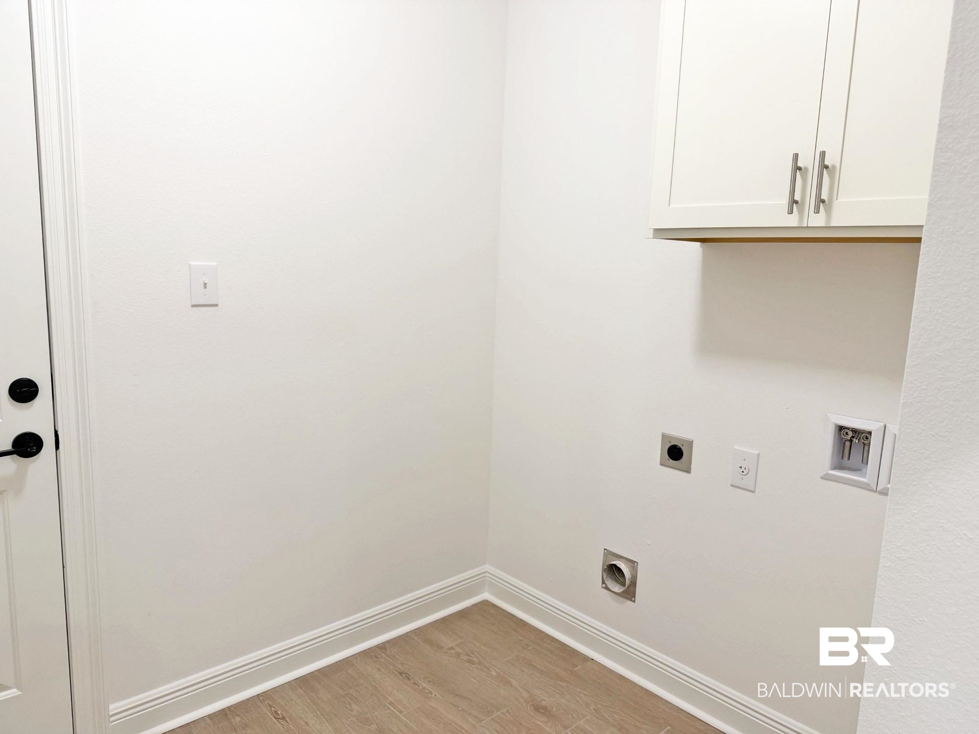 1753 Breckinridge Place Foley, AL 36535 - Photo 22 of 24 Utility area featuring wood-finish flooring, white baseboards, and built-in white cabinetry with brushed nickel hardware