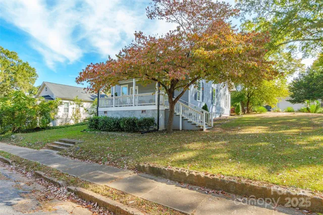 a view of a house with a big yard and large trees