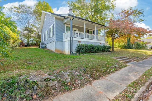 a view of a yard in front of a house with plants and large trees