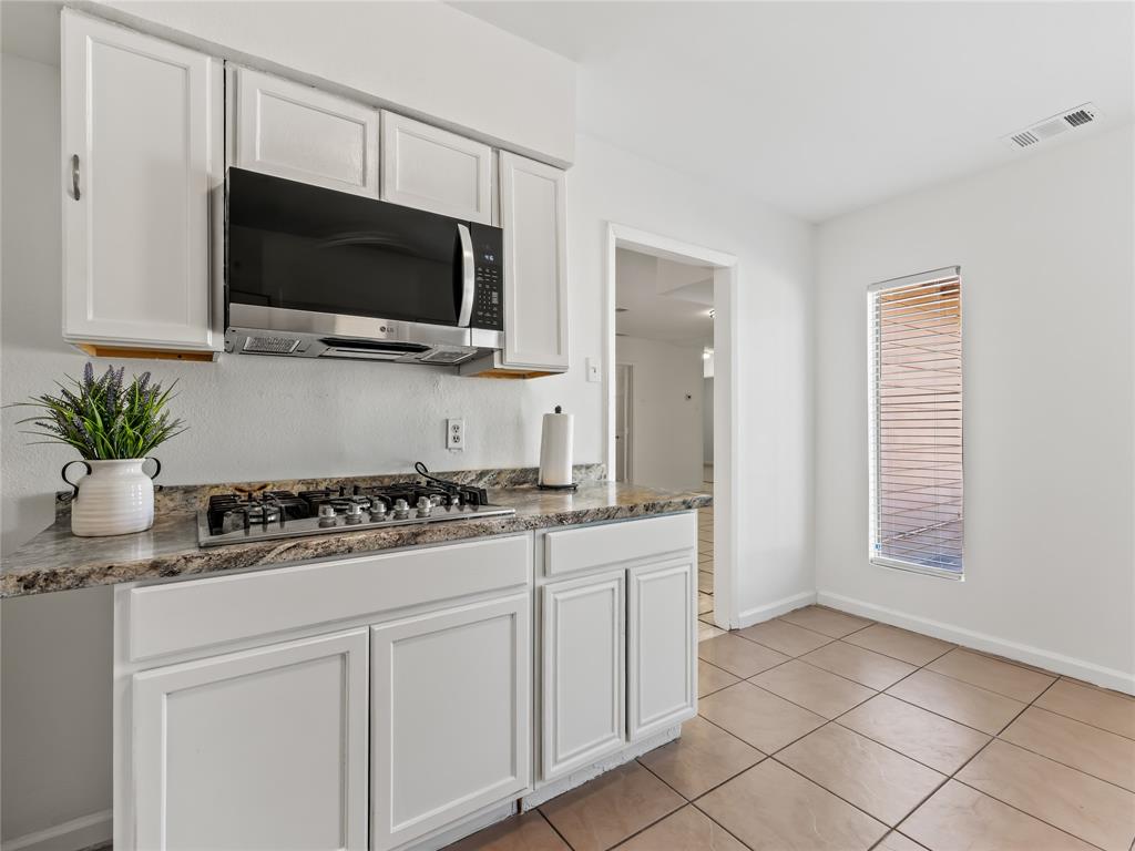 826 Ryan Road Dallas, TX 75224 - Photo 16 of 34 a kitchen with white cabinets and a stove top oven