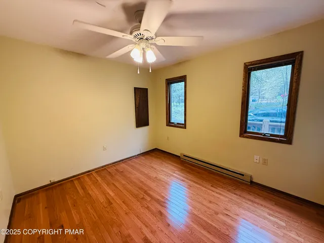 a view of an empty room with window and wooden floor