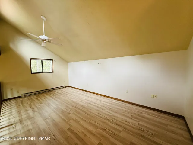 an empty room with wooden floor chandelier fan and windows