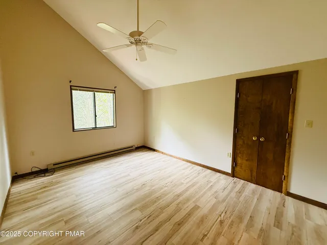 an empty room with wooden floor closet and windows