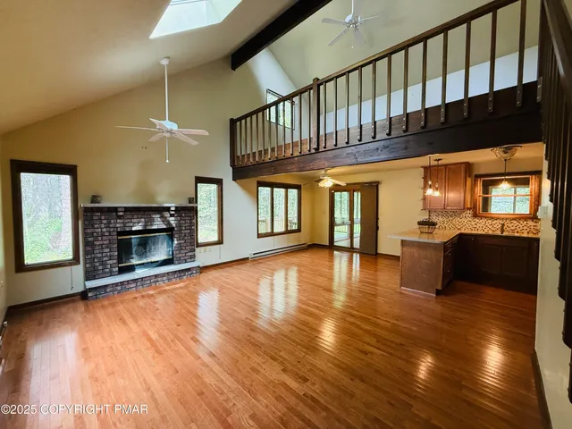 a view of a livingroom with a fireplace a ceiling fan and windows