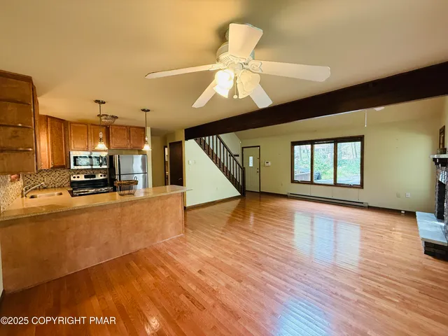 a view of a kitchen with wooden floor and a ceiling fan