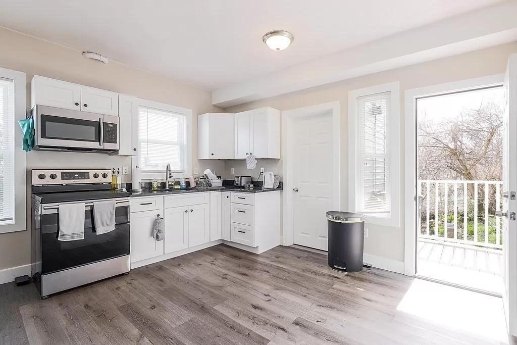 a kitchen with granite countertop a stove top oven a sink dishwasher a microwave oven and a cabinets with wooden floor