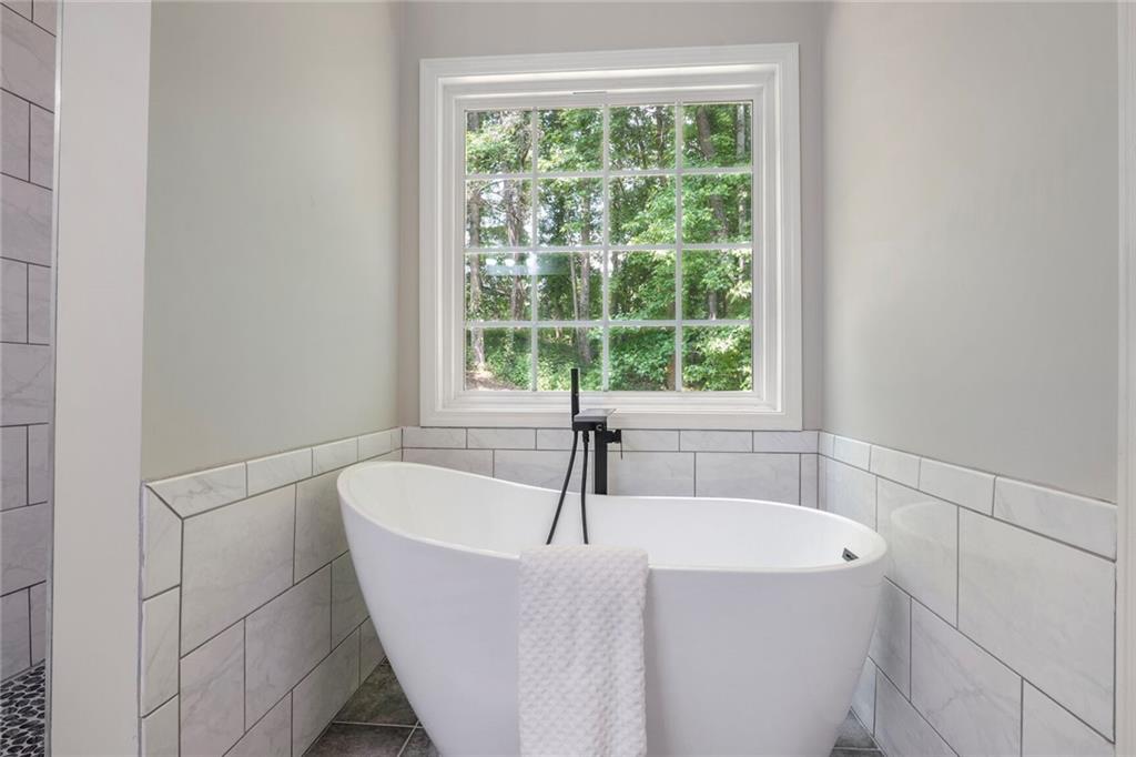 232 Barrett Springs Way Canton, GA 30115 - Photo 16 of 29 a white bath tub sitting in a bathroom next to a window