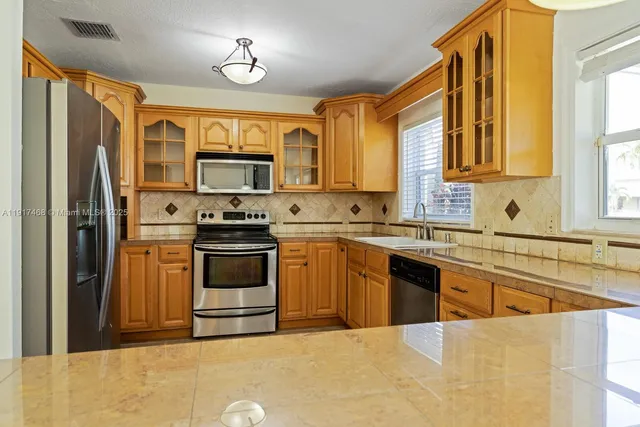 a kitchen with stainless steel appliances granite countertop a refrigerator a stove top oven a sink and dishwasher