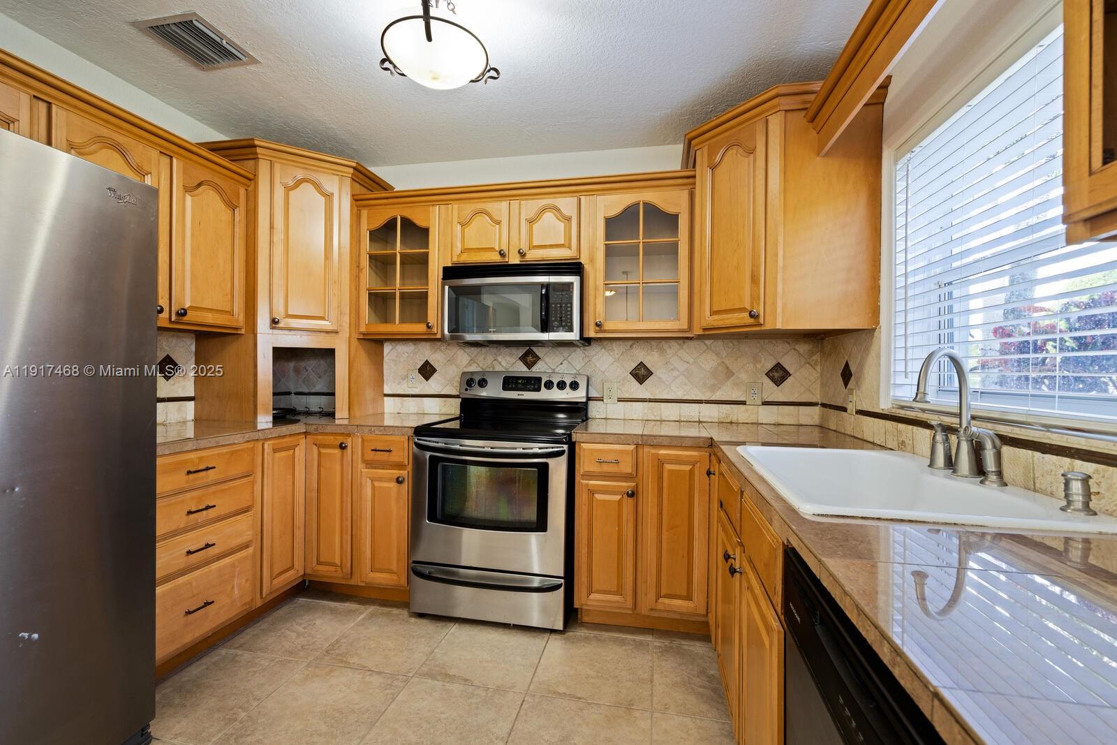 524 Northwest 14th Street Homestead, FL 33030 - Photo 5 of 37 a kitchen with stainless steel appliances granite countertop a sink stove microwave and refrigerator