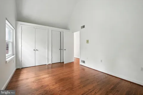 a view of an empty room with wooden floor and closet