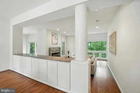a living room with furniture a potted plant and open kitchen view