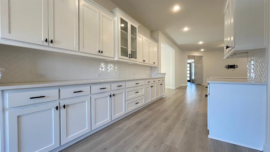 5304 Babcock Road McKinney, TX 75071 - Photo 6 of 27 a kitchen with white cabinets and wooden floor