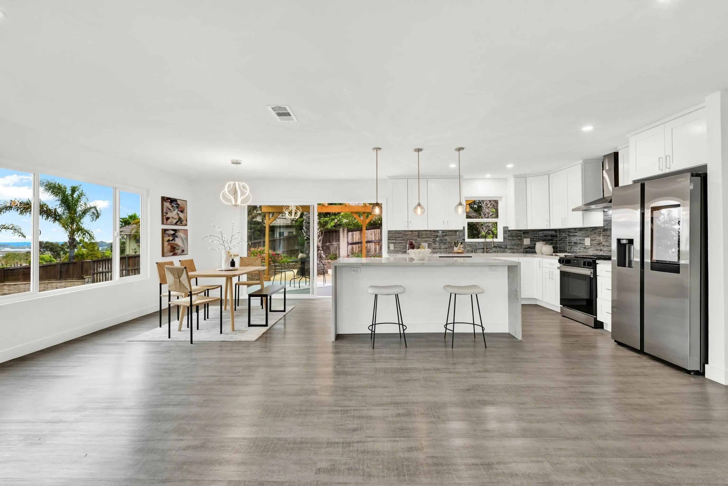 2250 Ivy Road Oceanside, CA 92054 - Photo 8 of 30 a kitchen with stainless steel appliances kitchen island granite countertop a refrigerator a stove a dining table and chairs with wooden floor