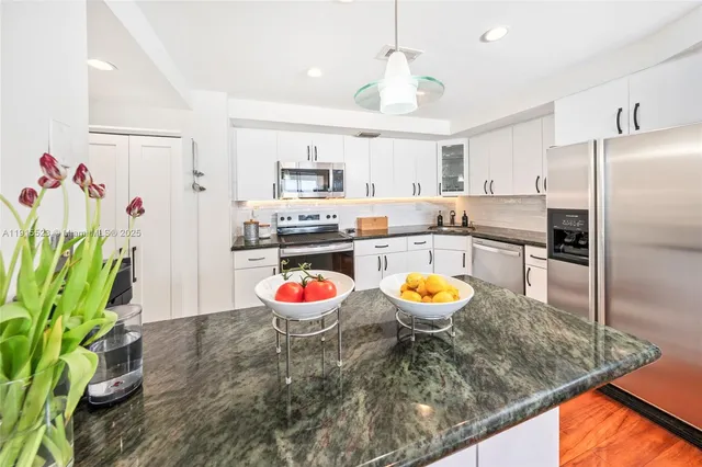 a kitchen with stainless steel appliances granite countertop a sink a stove and a refrigerator