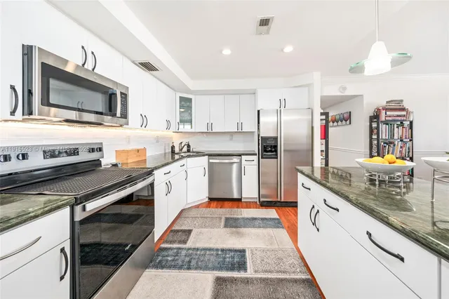 a kitchen with stainless steel appliances granite countertop a refrigerator a stove and a sink