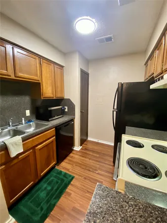a kitchen with granite countertop stainless steel appliances a stove a sink and a refrigerator