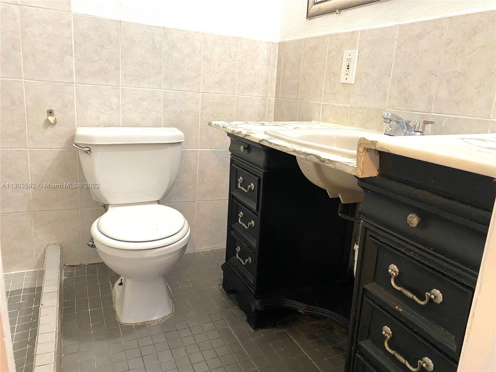 4763 Northwest 3rd Street, Unit 1A Miami, FL 33126 - Photo 11 of 14 a bathroom with a granite countertop toilet sink and mirror