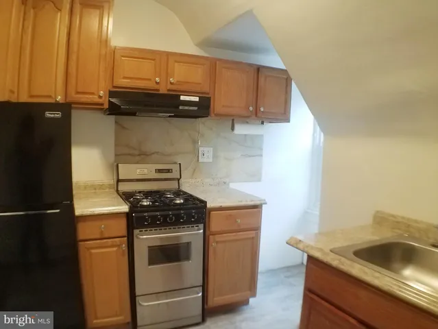 a kitchen with granite countertop a sink stove and cabinets