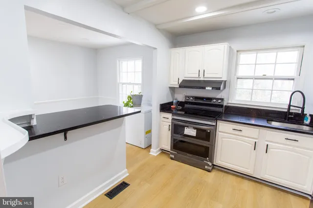 a kitchen with granite countertop a stove a sink and a microwave