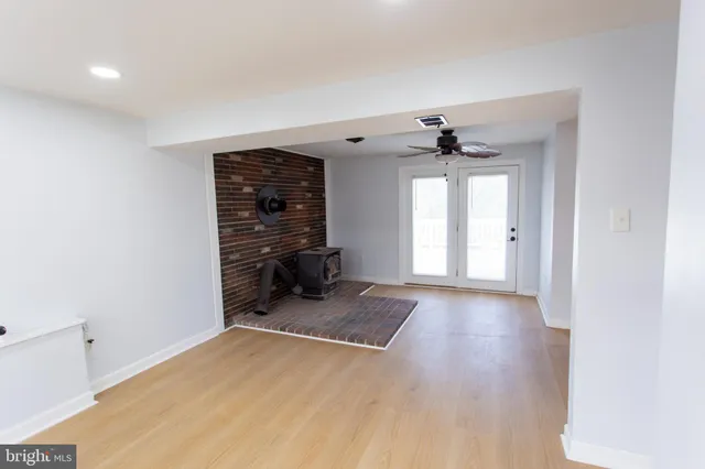 a view of a room with a ceiling fan window and a hallway