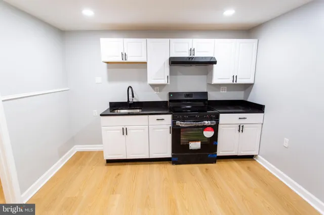 a kitchen with stainless steel appliances a stove a sink and white cabinets