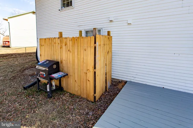 a backyard of a house with wooden table and chairs