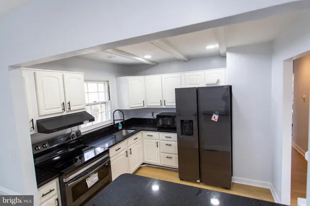 a kitchen with granite countertop a refrigerator and a stove top oven
