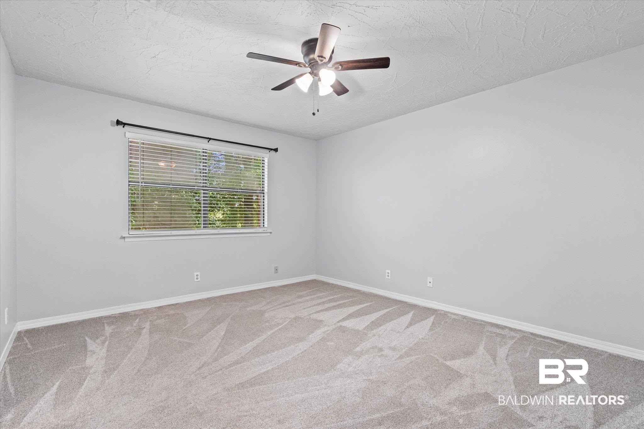 500 Grant Street, Unit C210 Daphne, AL 36526 - Photo 14 of 26 Spacious room featuring light gray walls, textured ceiling, and a contemporary ceiling fan with integrated lighting