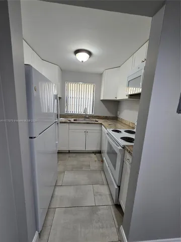 a kitchen with white cabinets and white appliances