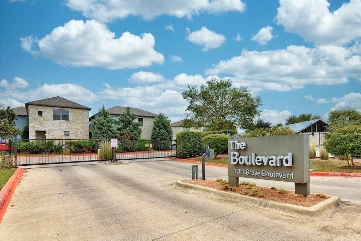 a sign board with a house in the background