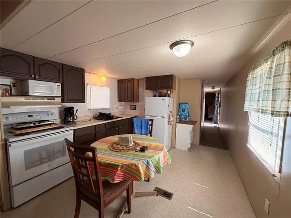 a kitchen with a table chairs refrigerator and microwave
