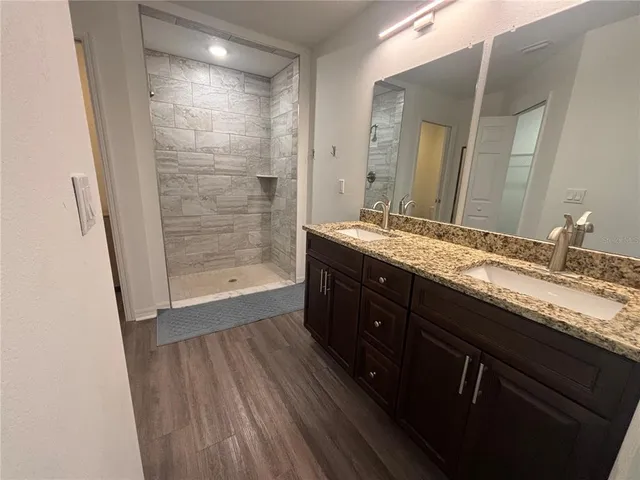a bathroom with a granite countertop sink a mirror and shower