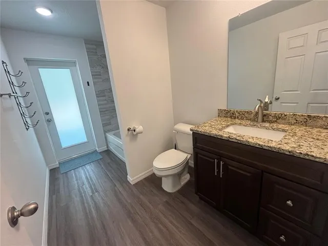 a bathroom with a granite countertop toilet a sink and a mirror