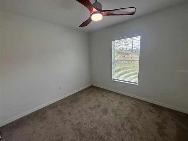 an empty room with a window and a fan