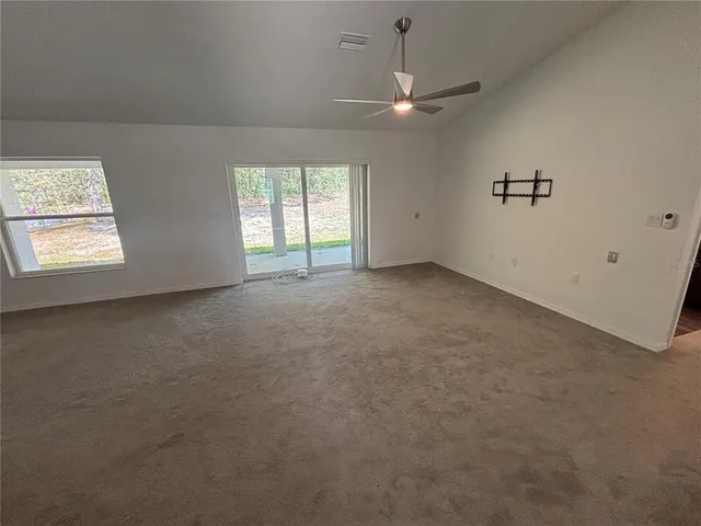 an empty room with windows and ceiling fan