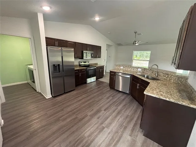 a large kitchen with stainless steel appliances granite countertop a sink and stove top oven