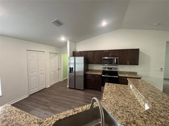 a kitchen with stainless steel appliances kitchen island granite countertop a refrigerator and a stove top oven