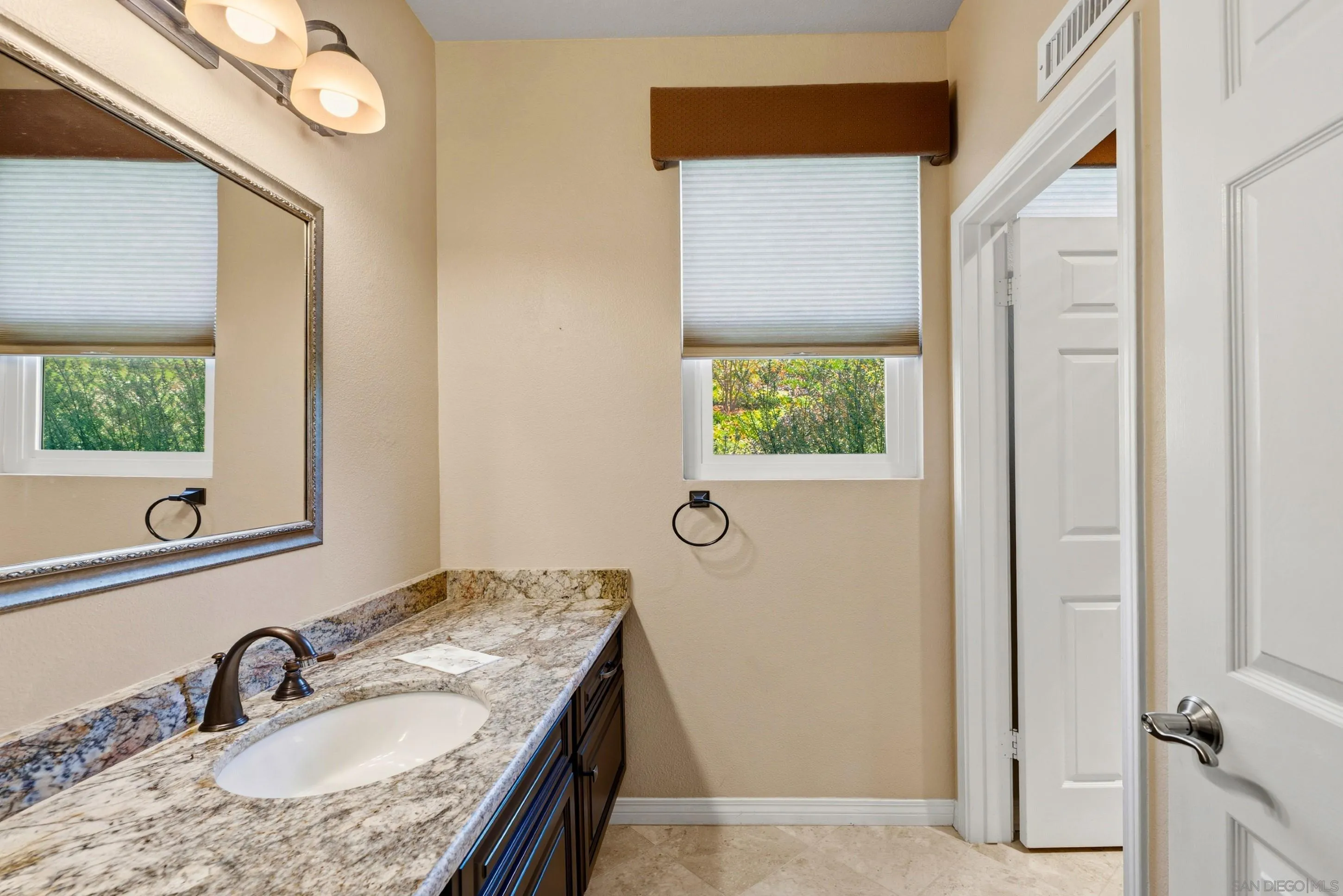 14505 Wildgrove Road Poway, CA 92064 - Photo 20 of 55 a bathroom with a granite countertop sink a mirror and a window