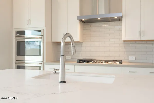 a kitchen with a refrigerator a stove and white cabinets