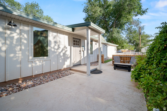 236 West 300 South Hurricane, UT 84737 - Photo 59 of 76 White vertical siding exterior with a covered entry, an exterior wall light fixture, a window with white trim, a decorative paneled door, and stamped concrete paving